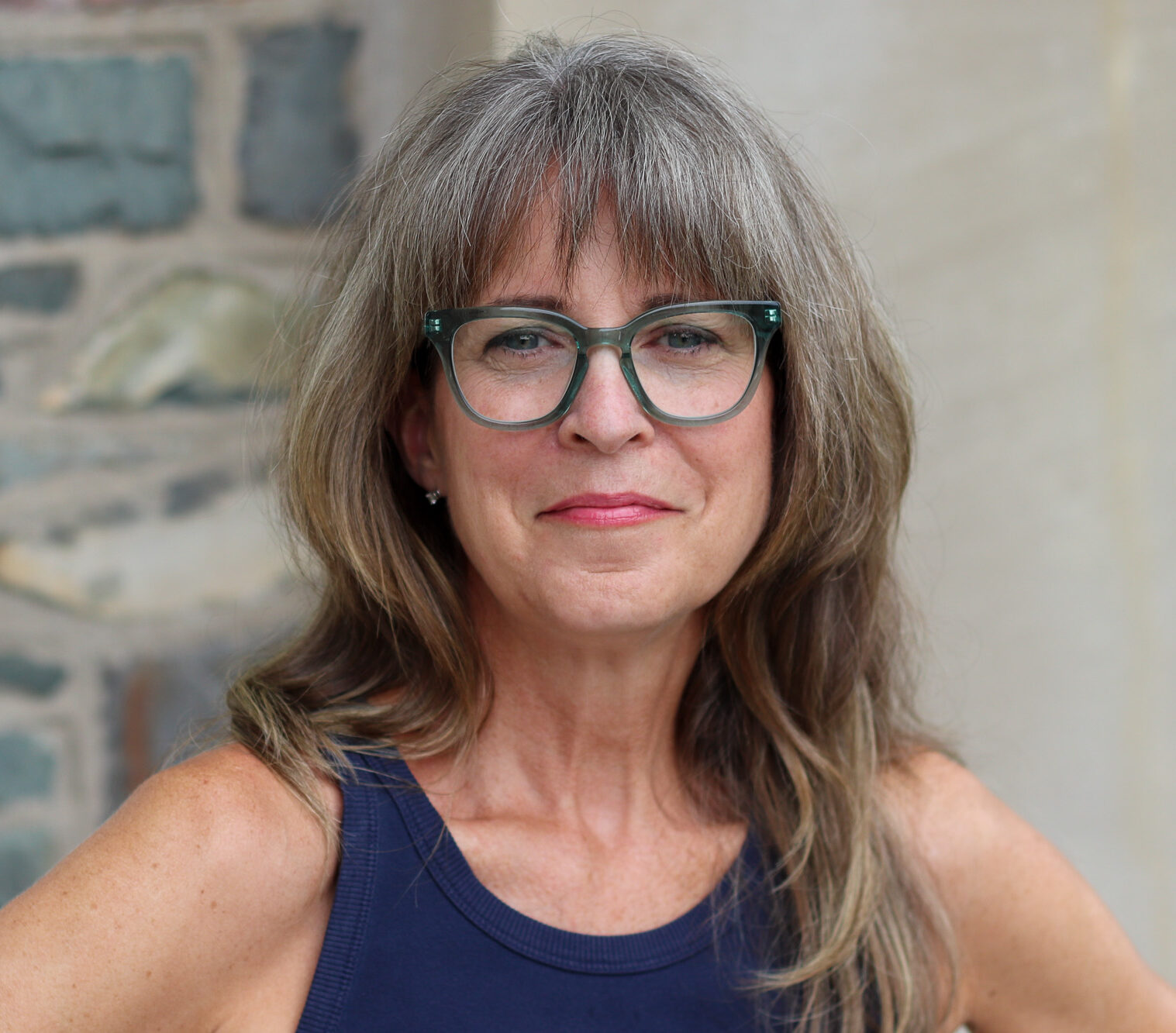 Photo d'une personne aux cheveux longs portant des lunettes et un débardeur bleu.