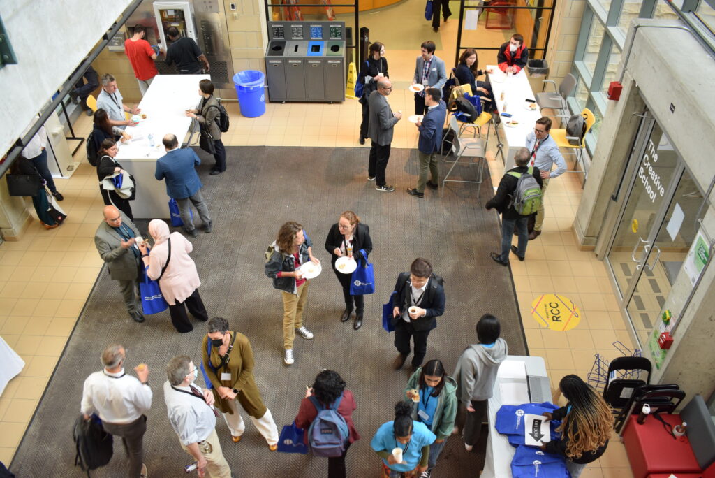 A bird's eye view of the Creative School Lobby with a group of individuals holding plates and blue bags