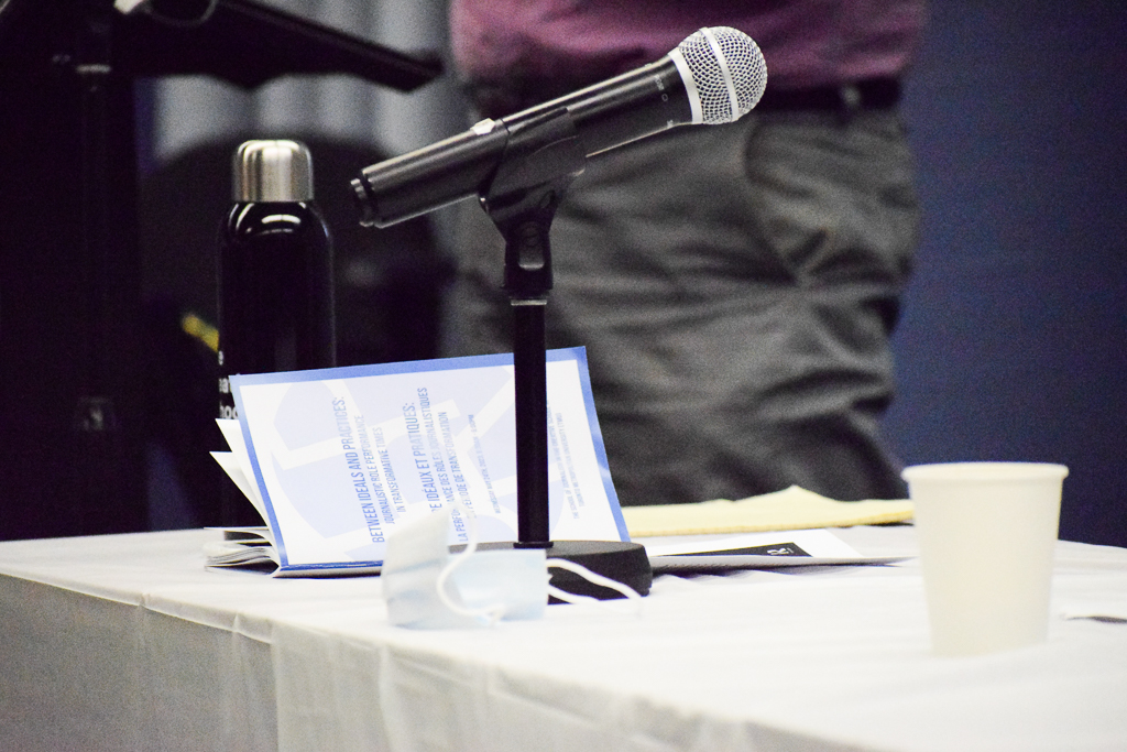 a microphone stand sits on a table with a white table cloth. In the foreground if a blue JRP pamphlet